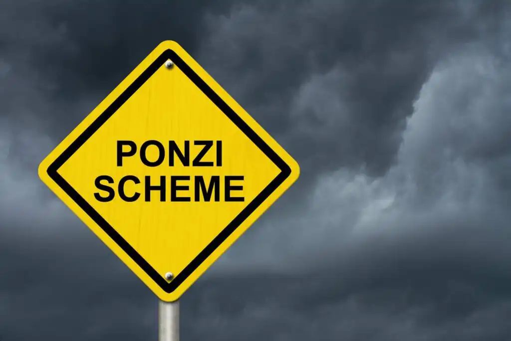 A yellow diamond-shaped road sign with the words PONZI SCHEME against a dark, cloudy sky background.