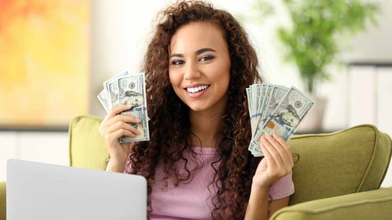 young woman with laptop holding bills