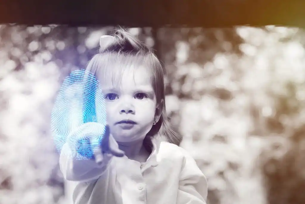A young child in a white shirt reaches forward, touching a glowing blue digital fingerprint graphic. The background is blurred with natural light and foliage, creating a soft, dreamy effect.