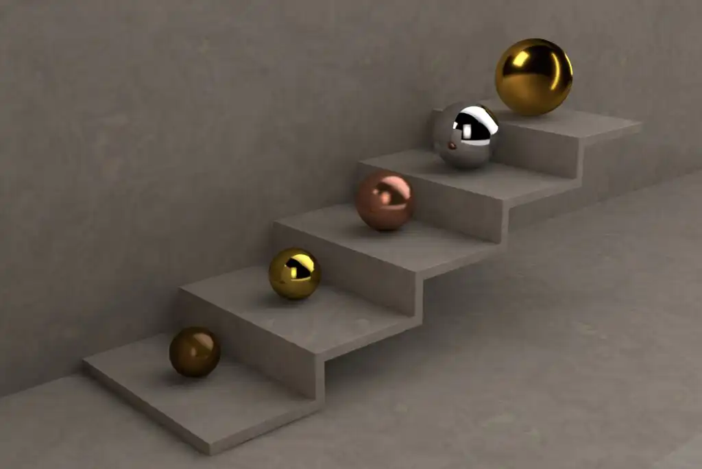 Five metallic spheres (gold, copper, silver, and bronze) are placed on and around a minimalist, stepped concrete staircase against a plain gray wall, creating a modern, abstract composition.