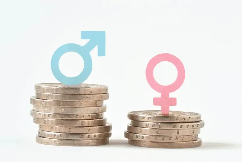 Stacks of coins with a blue male symbol atop a taller stack and a pink female symbol atop a shorter stack, representing the gender pay gap and income inequality between men and women.