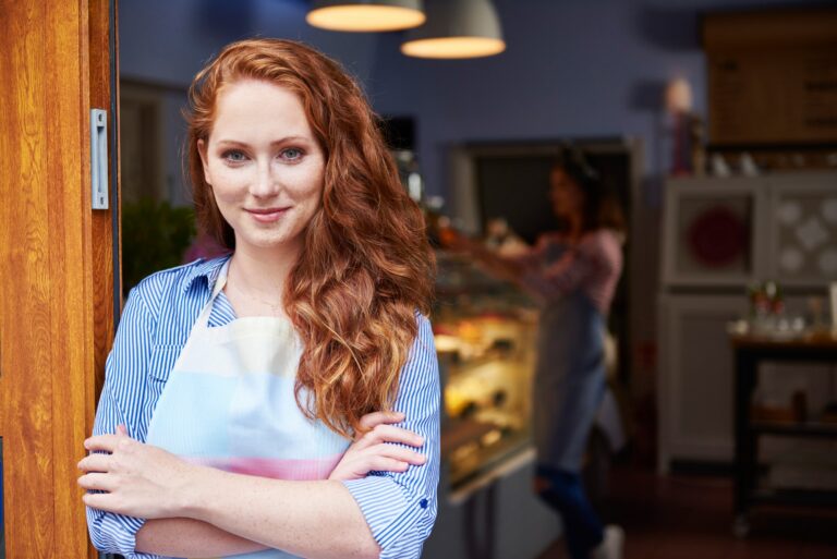 Portrait Of Smiling Young Woman At The Entrance Of A Bakery