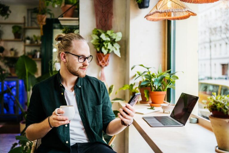 Man Using Smartphone While On Computer