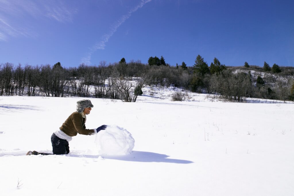 Woman Rolling Snowball For Snowman