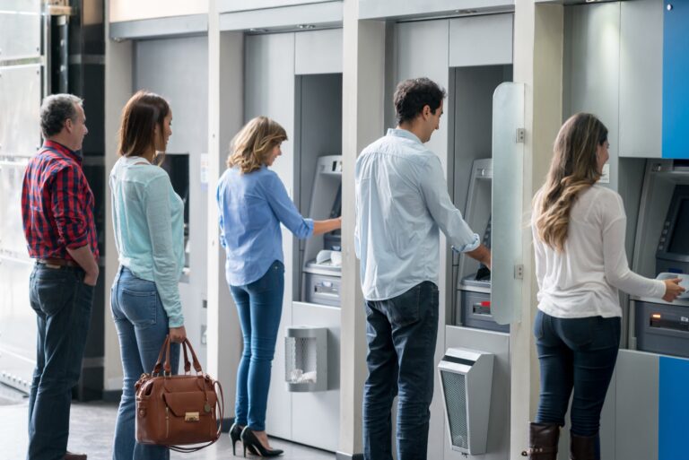 Group Of People In A Line At An Atm Waiting To Make A Cash Withdrawal