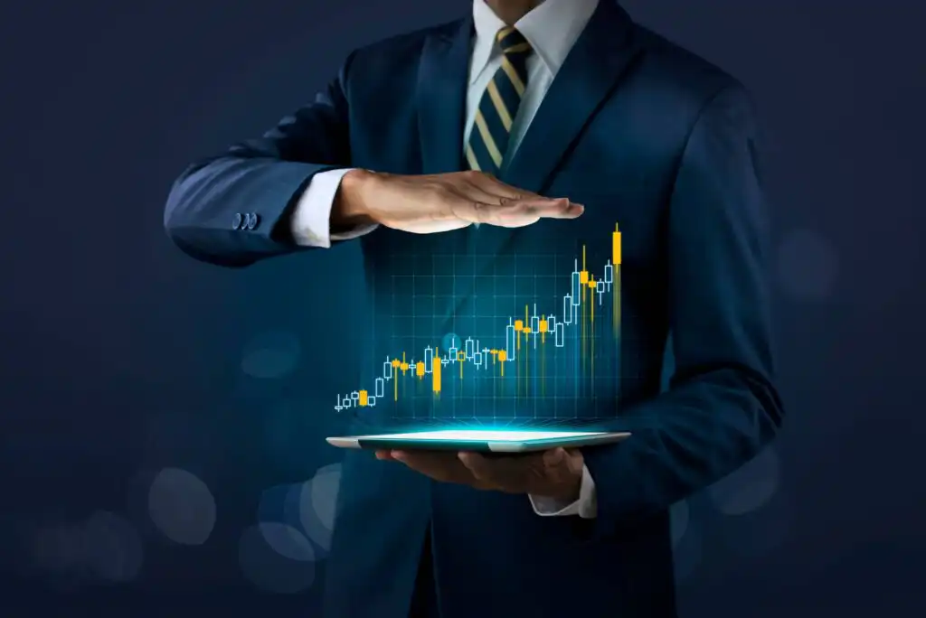 A person in a suit holds a tablet, above which a glowing upward-trending stock chart with candlesticks and data visuals appears, symbolizing financial growth and technology in business.