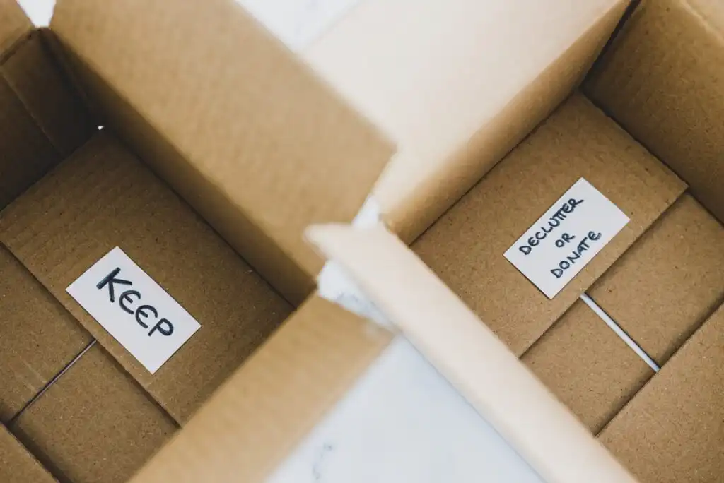 Two open cardboard boxes: one with a label reading KEEP, and the other with a label reading DECLUTTER OR DONATE. Both are empty and set side by side, viewed from above.