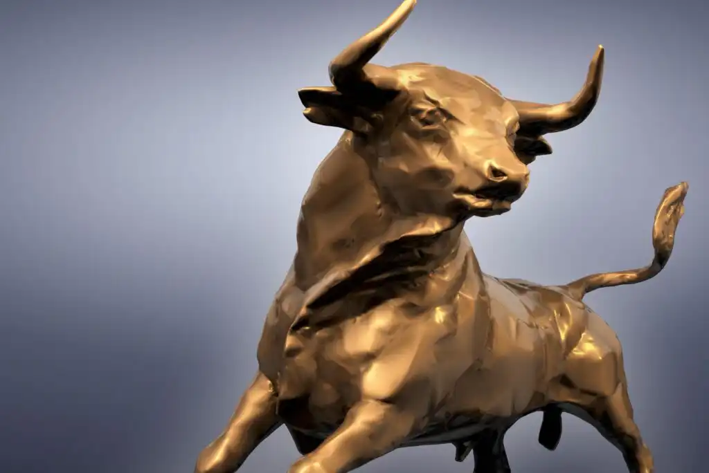 A bronze-colored bull statue stands against a gradient gray background, symbolizing strength and confidence. The bull’s head is raised and its body is poised as if in motion.