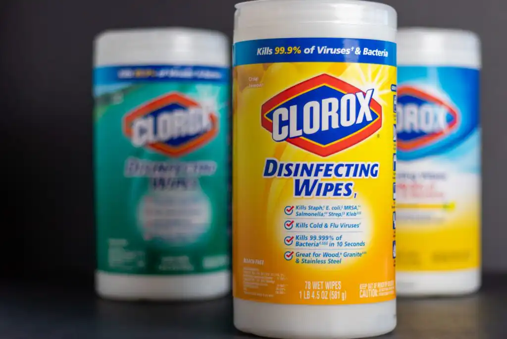A close-up of three canisters of Clorox disinfecting wipes, with the yellow-labeled canister in focus, displaying the brand name and product details, while two other canisters are blurred in the background.