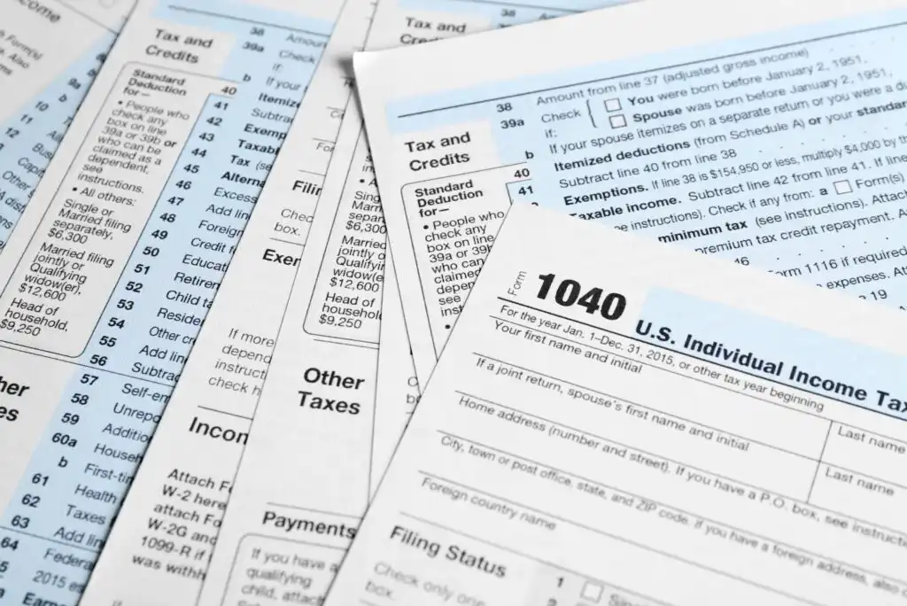 A close-up of several U.S. tax forms and instruction sheets, including a prominent 1040 Individual Income Tax Return form, all spread out on a flat surface.