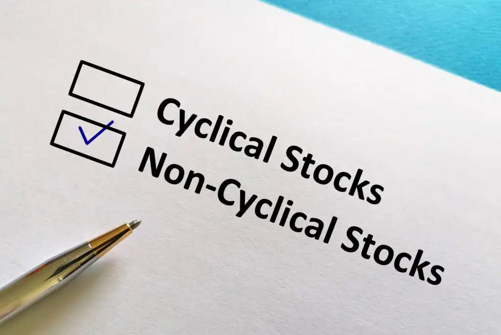 A checklist on paper with two options: Cyclical Stocks (checked) and Non-Cyclical Stocks (unchecked), next to a pen on a white and blue background.