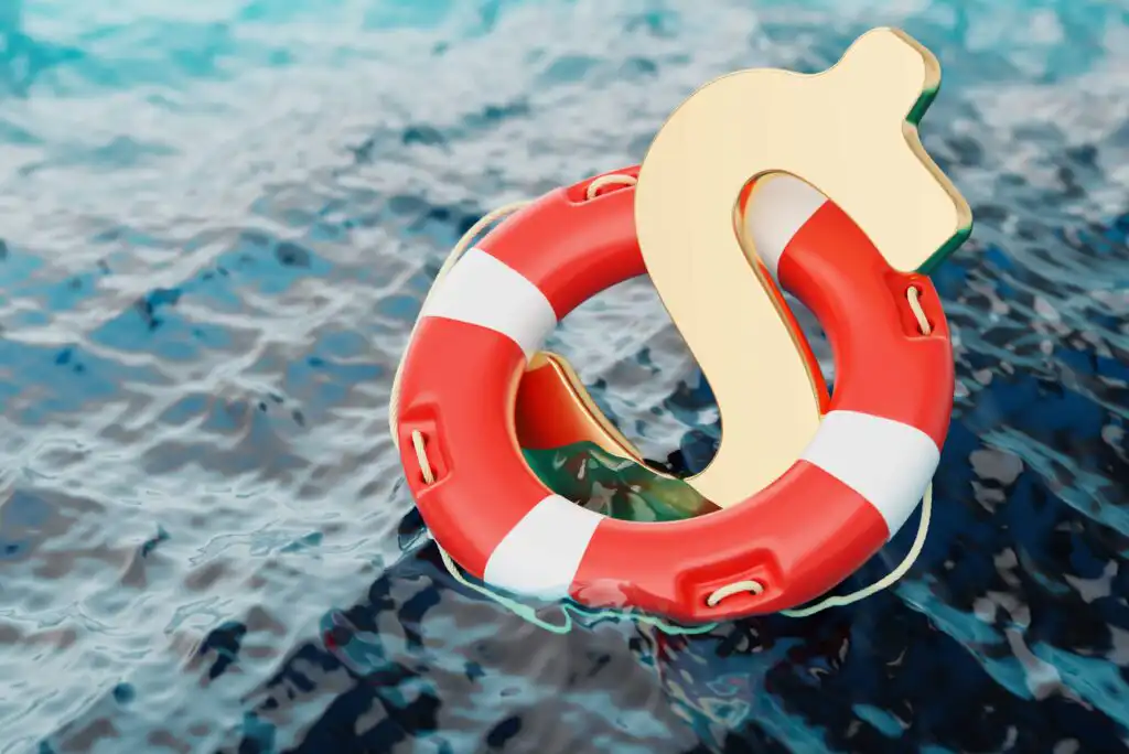 A golden dollar sign is floating upright inside a red and white lifebuoy ring on the surface of blue water, symbolizing financial rescue or support.