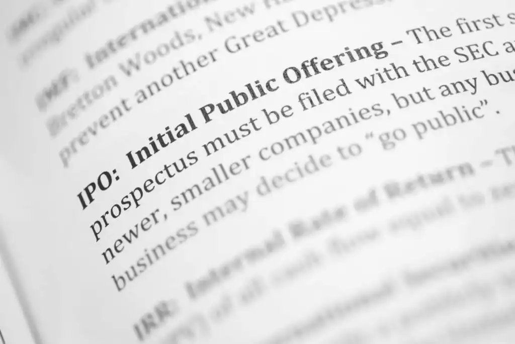 Close-up of a book page with the bolded heading IPO: Initial Public Offering followed by text explaining that a prospectus must be filed with the SEC and smaller companies may decide to go public.