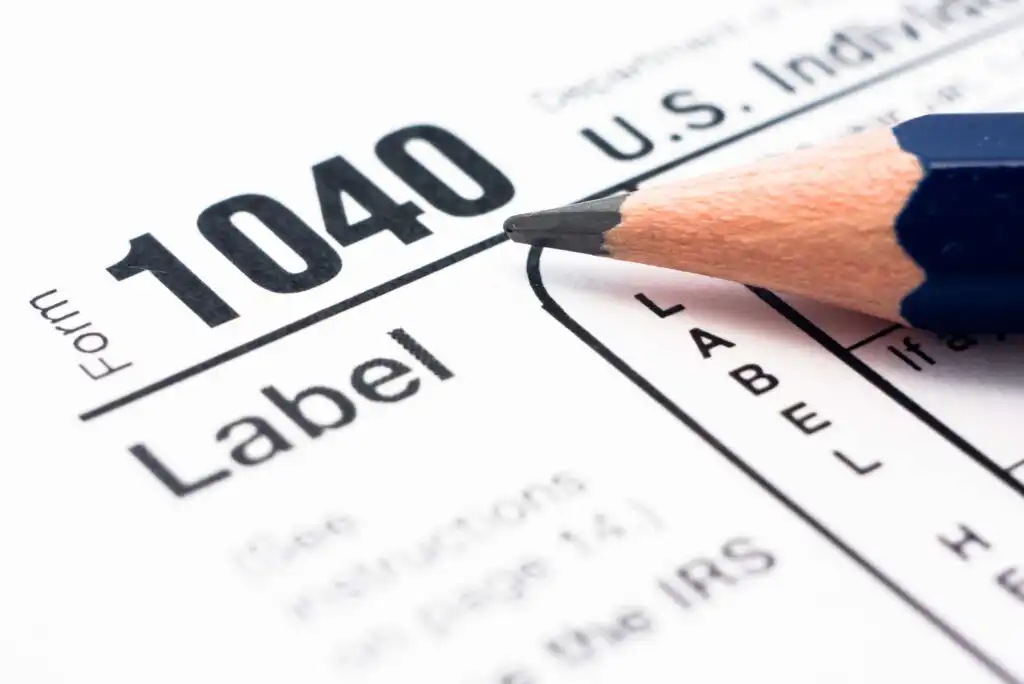 A sharpened pencil rests on a U.S. IRS Form 1040 tax document, with the word Label and part of the tax form visible.