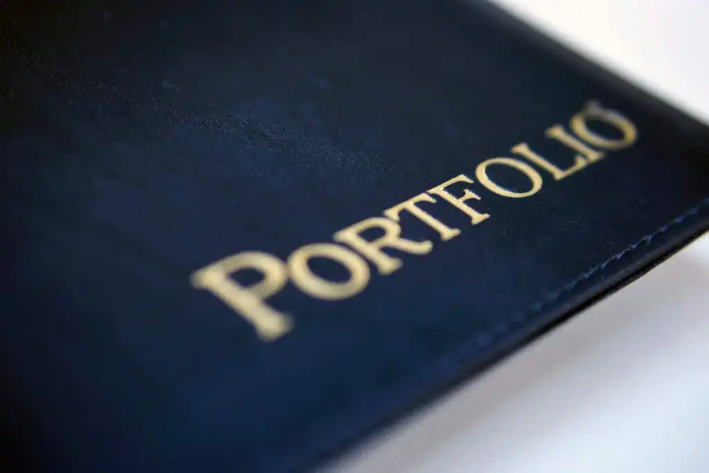 Close-up of a navy blue folder or binder with the word PORTFOLIO embossed in gold letters on the cover.