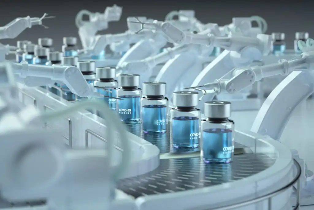A row of robotic arms assemble and handle vials labeled COVID-19 Vaccine on a conveyor belt in a sterile, high-tech laboratory setting.