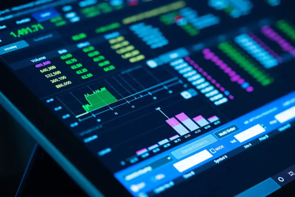 A close-up of a digital screen displaying colorful stock market data, including charts, graphs, fluctuating numbers, and financial statistics.