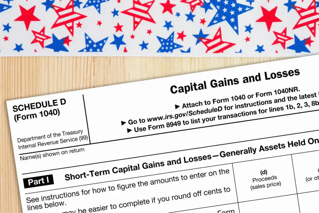 A partial view of IRS Schedule D tax form labeled Capital Gains and Losses, next to a decorative surface with red and blue star patterns.