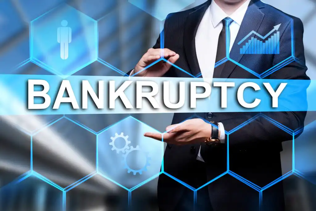 A man in a suit stands behind a transparent screen with icons and the word BANKRUPTCY in large letters, symbolizing financial crisis and business concepts.