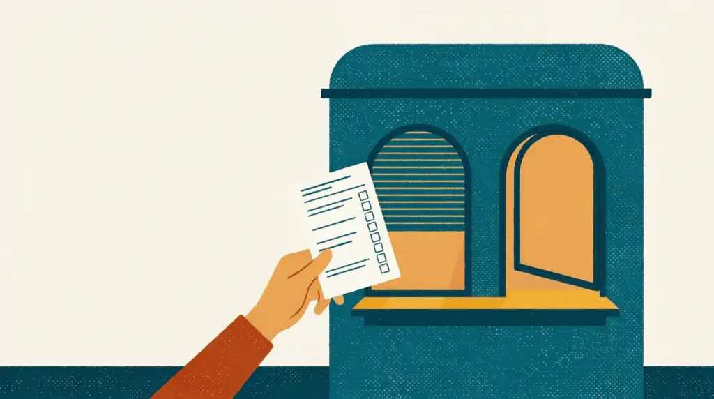 Hand holding an application form up to a teal ticket booth with one shuttered window and one open window