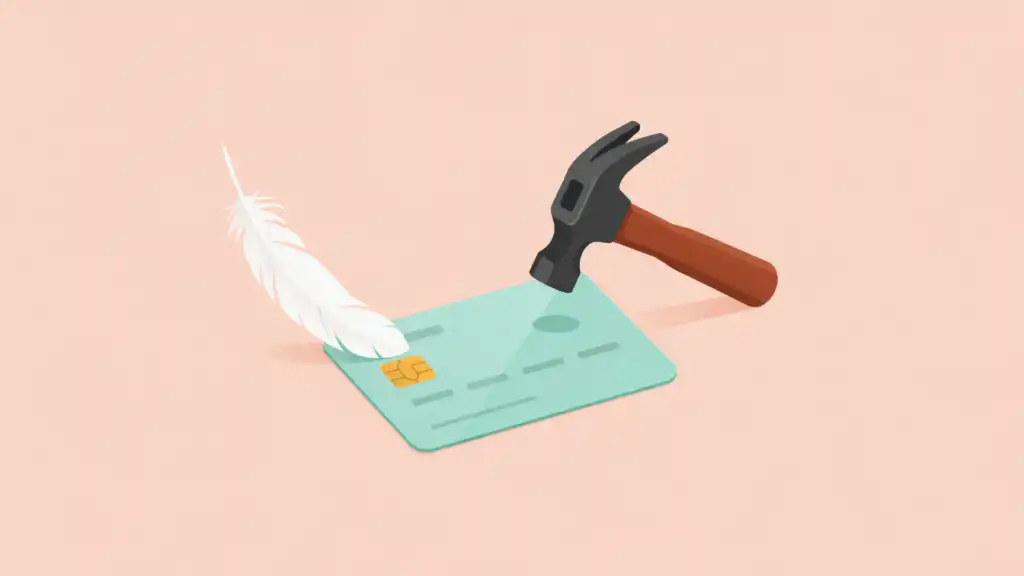 A white feather rests on a mint credit card while a charcoal hammer hovers raised above it