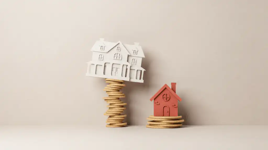A white mansion tilts atop a tall, wobbly tower of gold coins beside a small red cottage on a short, wide coin stack