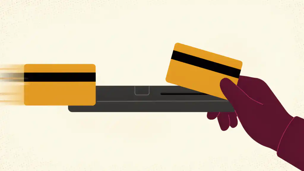 A credit card with a magnetic stripe slides into a reader while its duplicate comes out into a gloved hand