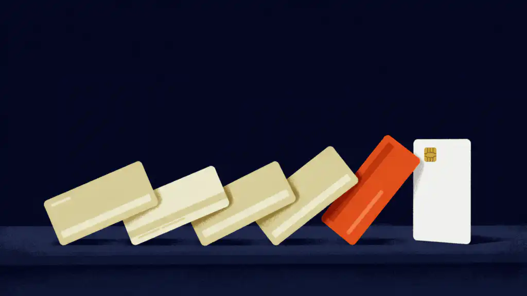 A chain of toppling credit cards about to knock over a white card still standing at the end