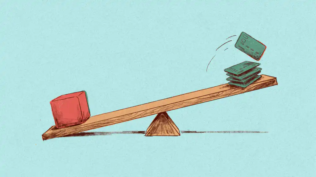A seesaw tipped toward a red weight as one green credit card lifts off the stack on its raised end
