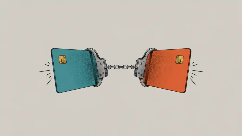 Teal and orange credit cards locked together by a pair of steel handcuffs