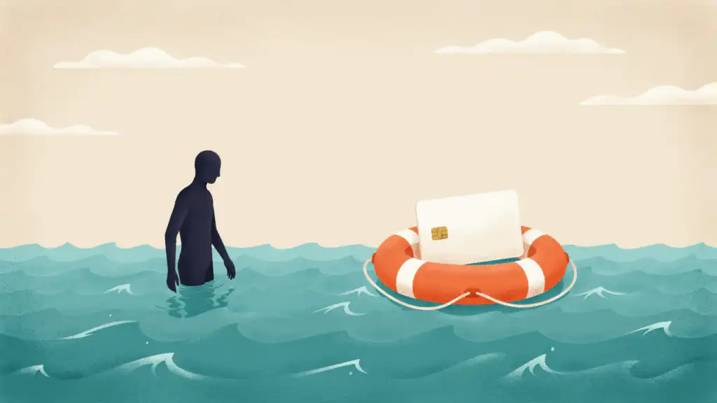 An orange life ring floats around a credit card while a person stands waist-deep in the sea nearby without one