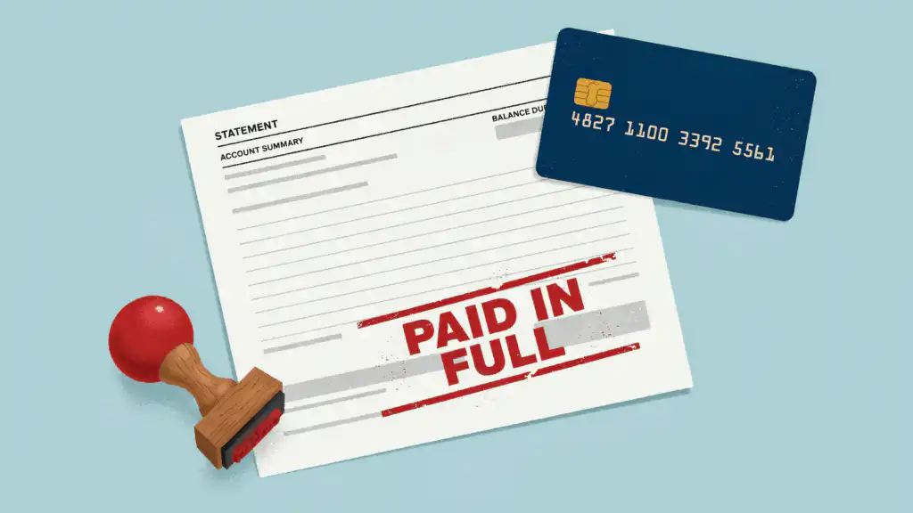 A credit card statement stamped PAID IN FULL in red ink, with a navy credit card resting on its corner