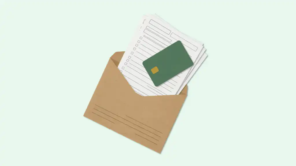 A kraft envelope holds a stack of tax forms with a green credit card resting on top.