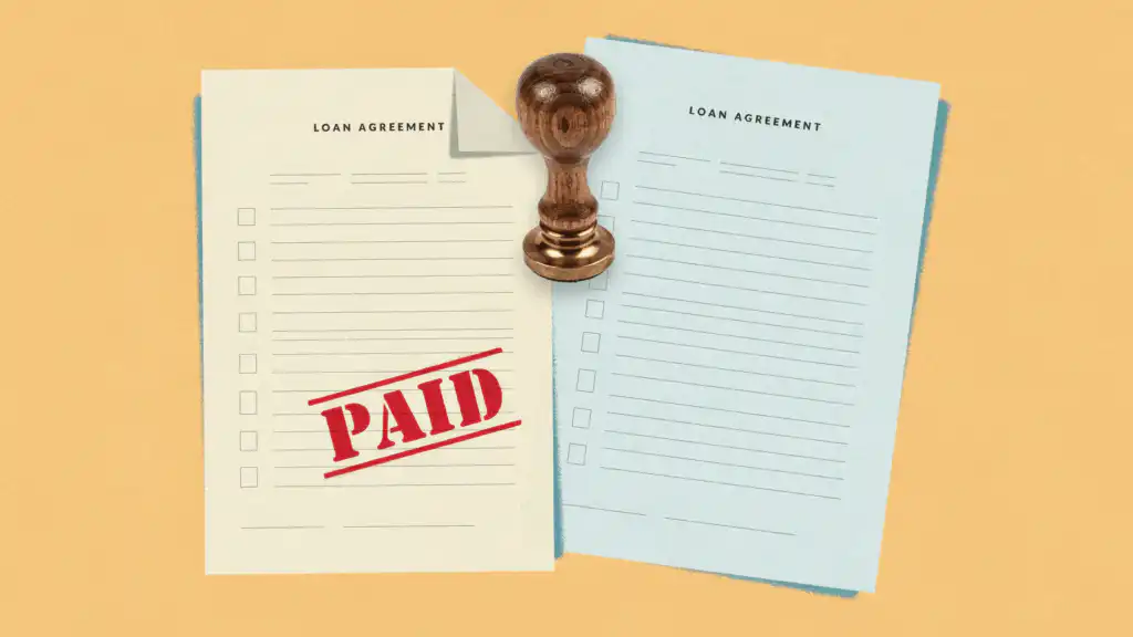 Loan agreement stamped PAID next to an unstamped blue loan agreement, a wooden rubber stamp between them