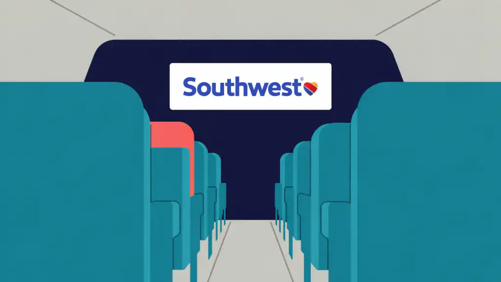 Southwest logo on the front wall of an airplane cabin, seen down an aisle of teal seats with one coral seat