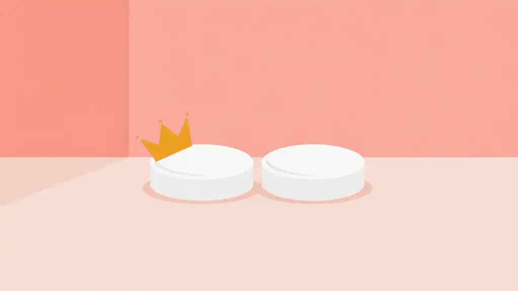 Two identical white medicine tablets on a blush tabletop, the left one wearing a small gold crown